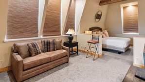 Un dormitorio con cama, sofá, sillón y escritorio con lámpara.