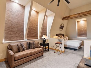 Ein Schlafzimmer mit Bett, Sofa, Sessel und Schreibtisch mit Lampe.