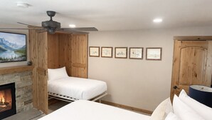A bedroom with a fireplace, a bed, a ceiling fan, and framed pictures on the wall. - Resort Center 5058 | Amazing Ski-In/Ski-Out with Mountain Views & Pool Access (Park City)