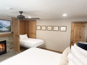 A bedroom with a fireplace, a bed, a ceiling fan, and framed pictures on the wall. - Resort Center 5058 | Amazing Ski-In/Ski-Out with Mountain Views & Pool Access (Park City)