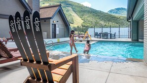 A swimming pool with a view of a mountain. There are Adirondack chairs and a table with chairs around the pool. - Resort Center 5058 | Amazing Ski-In/Ski-Out with Mountain Views & Pool Access (Park City)