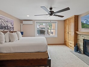 A bedroom with a bed, a ceiling fan, a window, wooden cabinets, and a fireplace. - Resort Center 5058 | Amazing Ski-In/Ski-Out with Mountain Views & Pool Access (Park City)