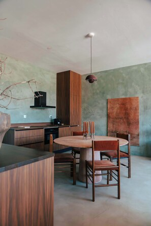 Una cocina moderna con armarios de madera, una mesa de comedor con sillas y una lámpara colgante.