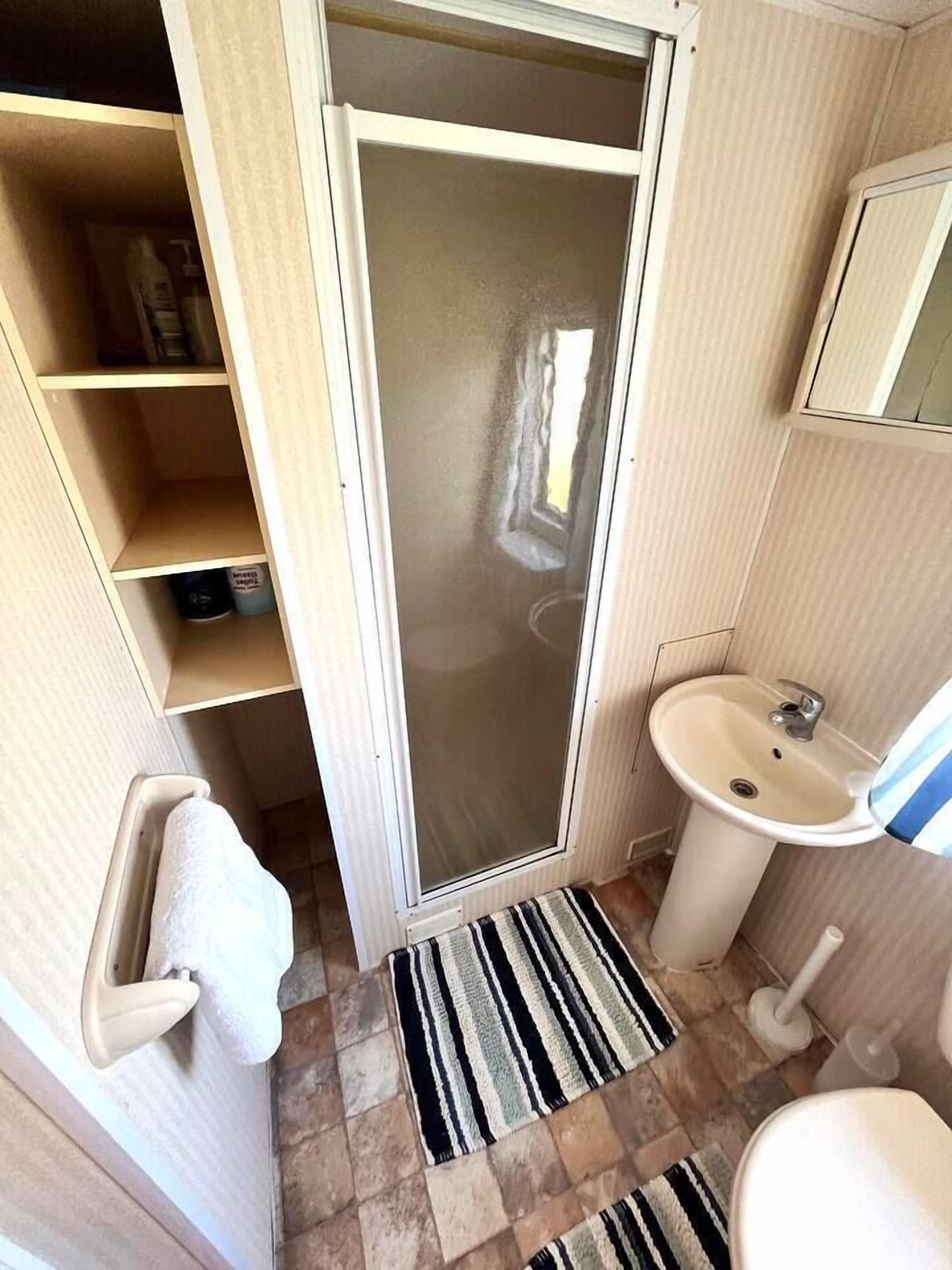 Een kleine badkamer met toilet, wastafel en douchecabine.