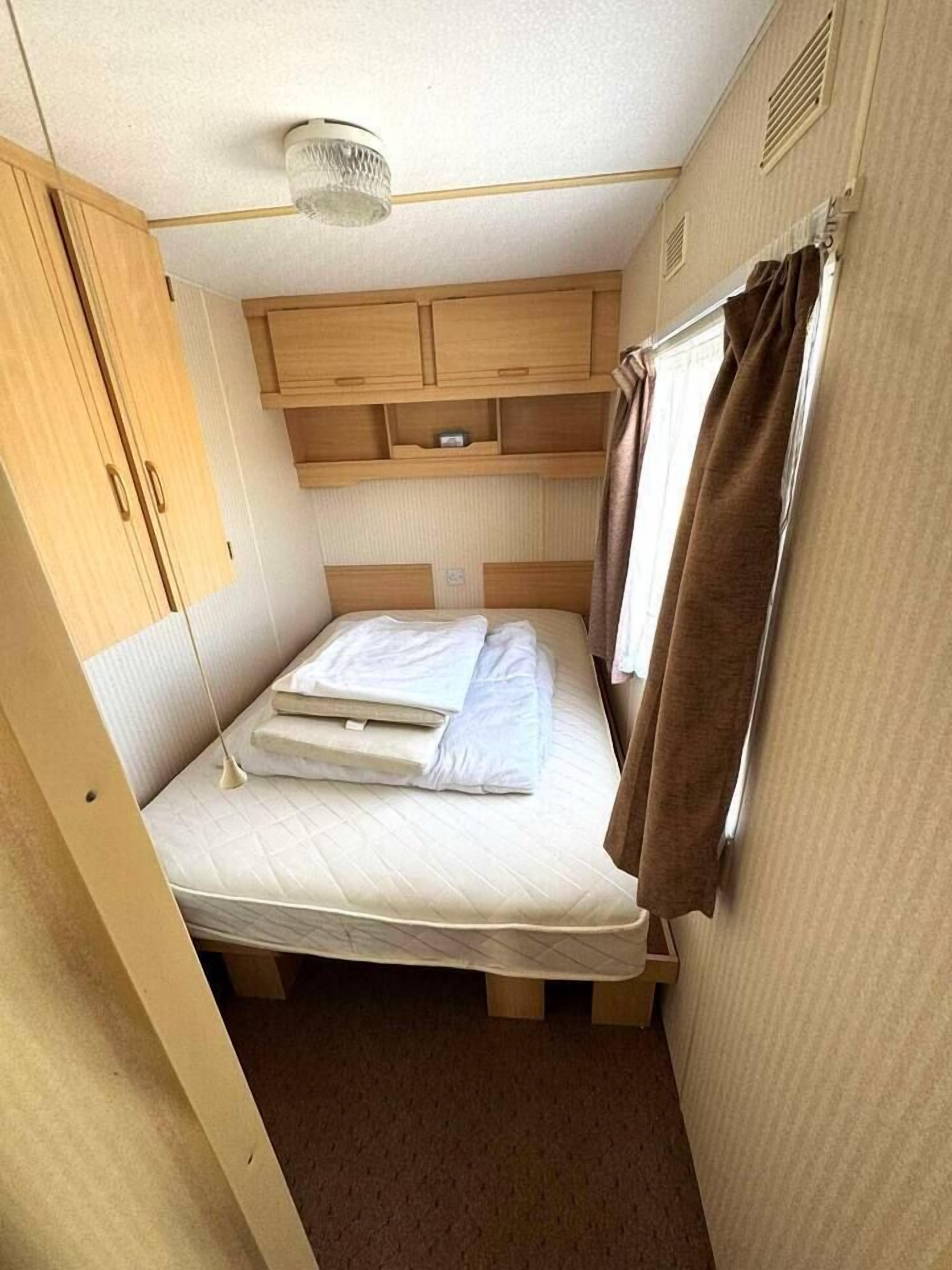 Une chambre à coucher de taille modeste, comprenant un lit simple, une petite armoire et un luminaire fixé au plafond.