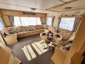Un interior de caravana acogedor, con sofá, mesa de comedor y zona de cocina.
