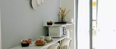 A kitchen with a white countertop, a microwave, a white chair, and a window with a view.