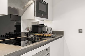 A modern kitchen with a built-in stove, coffee maker, and a kettle. - Marylebone's Gold - 3 Bed (Greater London)