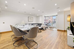 A modern dining area with a rectangular table set for four, surrounded by upholstered chairs with metal legs. - Marylebone's Gold - 3 Bed (Greater London)