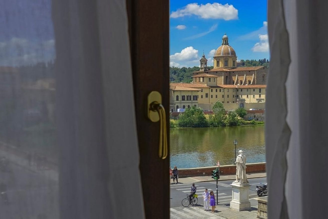 Una vista attraverso una porta che mostra un edificio, una distesa d'acqua e una statua in primo piano.