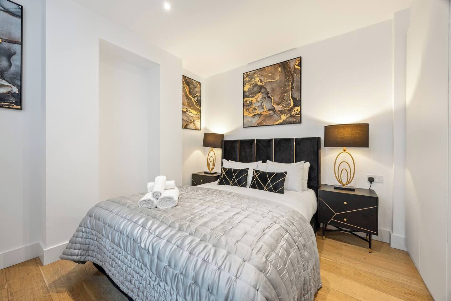 A modern hotel room with a large bed, two bedside tables, and artwork on the walls.