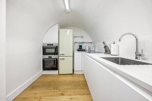 A narrow kitchen with white cabinetry, a sink, and a countertop. - Gloucester place 2Bed Apartment (Greater London)