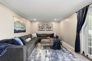 A living room with a sectional sofa, a coffee table, and artwork on the wall.