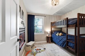 A child's bedroom with bunk beds, a toy storage unit, and a window with curtains. - Hidden Haven (Liverpool)