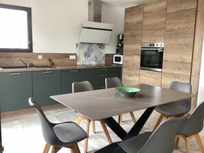 Eine moderne Küche mit Essbereich, ausgestattet mit einer Kochinsel, integrierten Geräten und einem großen Fenster.