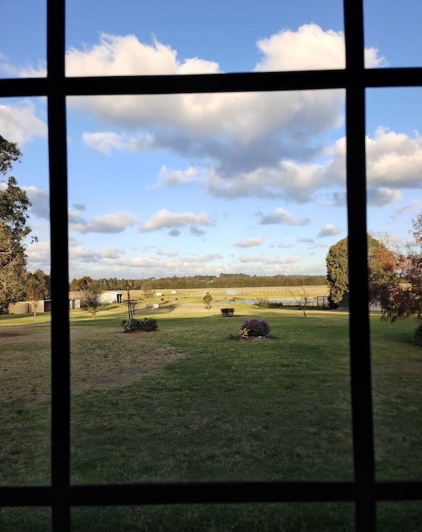 A view through a window of a grassy field with trees and a clear sky. - Hunter Valley Nulkaba | breathtaking views & relax (Nulkaba)