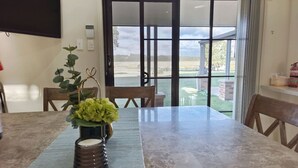 A dining area with a table, chairs, a TV mounted on the wall, and a view through a glass door. - Hunter Valley Nulkaba | breathtaking views & relax (Nulkaba)