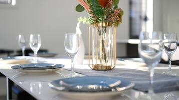 A dining table set with plates, cutlery, and glasses, with a decorative vase in the center.