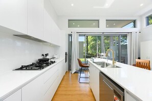 A modern kitchen with white cabinets, a stove, and a large window.