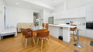 Een modern appartement met een eethoek, kitchenette en een zithoek met een bank en een bed.