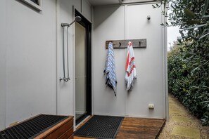 Ein modernes Badezimmer mit Dusche, einem Handtuchhalter mit zwei Handtüchern und einer Holzbank.