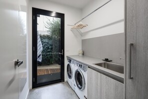 Ein kleiner Waschraum mit Waschmaschine, Wäscheständer und Waschbecken.