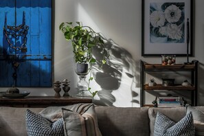 Ein Wohnzimmer mit einer Couch, einem Blumentopf, einer blauen Wand und einem gerahmten Bild.