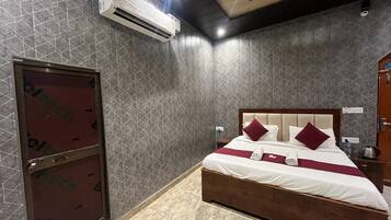 A hotel room with a bed, a wardrobe, an air conditioning unit, and a tiled wall.