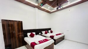A bedroom with two beds, a wardrobe, and a ceiling with recessed lighting. - Roomshala Shreeji Palace  (Ayodhya)