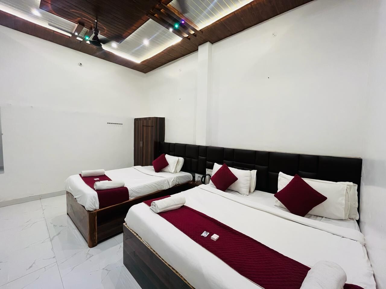 A hotel room with two beds, a wardrobe, and a ceiling light fixture.