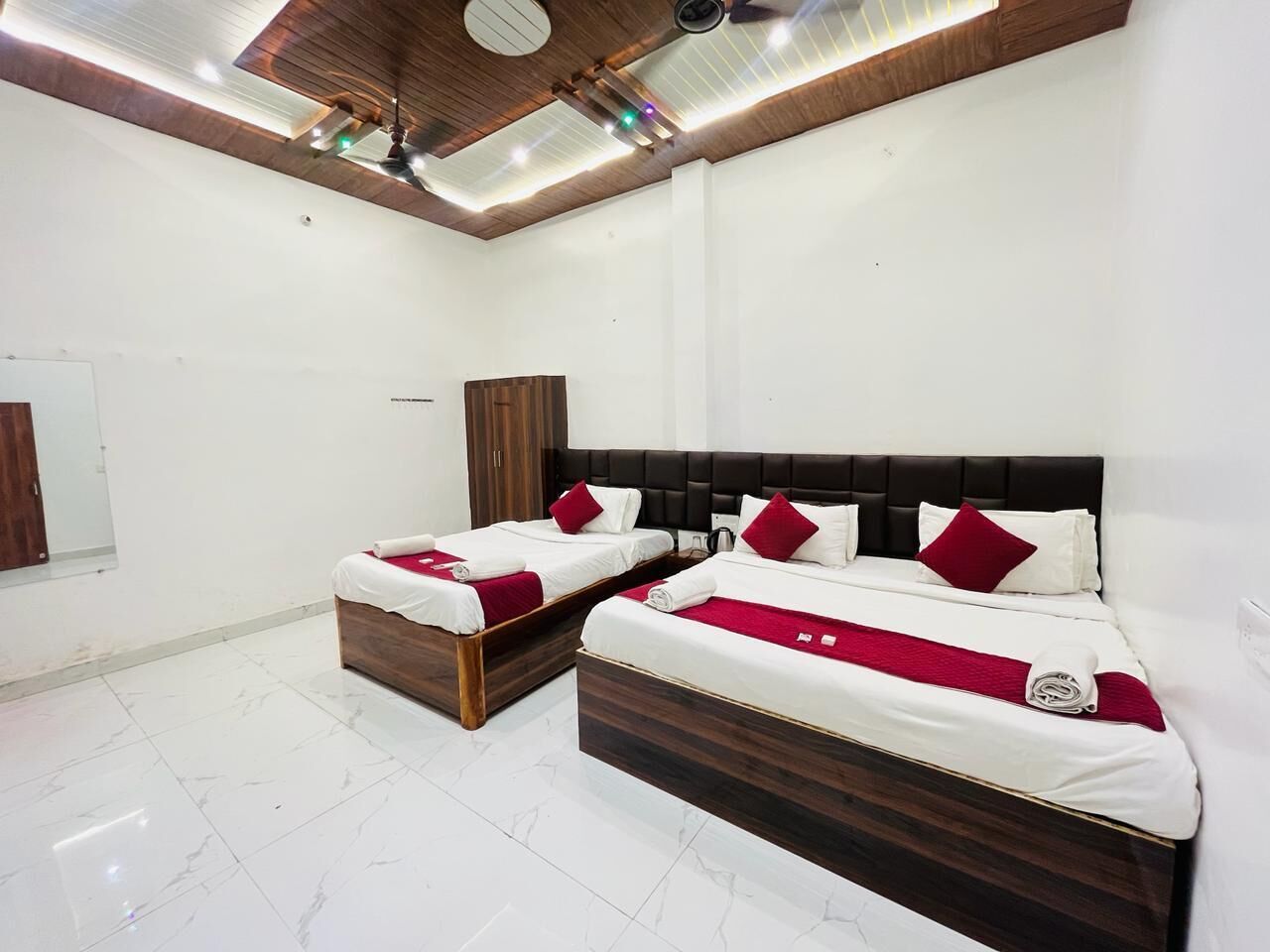 A hotel room with two beds, a wooden headboard, white bedding, and a red throw blanket.