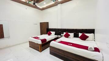 A hotel room with two beds, a wooden headboard, white bedding, and a red throw blanket.