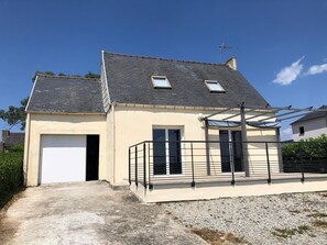 A two-story house with a garage, a balcony with a metal railing, and a sloped roof with skylights. - Holiday Home 'Maison De Vacances Crozon Jardin' with Sea View, Private Terrace and Wi-Fi (Crozon)