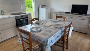 Een keuken met een eettafel voor twee personen, een kookplaat, oven en een koelkast.