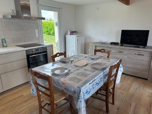 Eine Küche mit Esstisch für zwei Personen, einem Herd, Backofen und einem Kühlschrank.