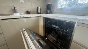 Een keuken met een vaatwasser, een koffiezetapparaat en een waterkoker op het aanrecht.