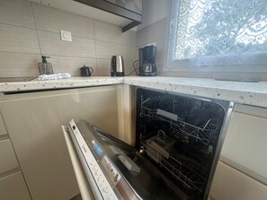 Eine Küche mit Spülmaschine, Kaffeemaschine und Wasserkocher auf der Arbeitsfläche.