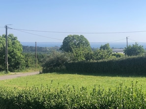 A rural road with a grassy field, trees, and a distant view of a house. - Holiday Home 'Maison De Vacances Crozon Jardin' with Sea View, Private Terrace and Wi-Fi (Crozon)