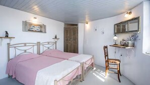 A bedroom with two beds, a chair, a shelf with items, and a mirror on the wall. - TWIN OVEN APARTMENT (messaria)