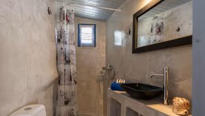 A compact bathroom with a toilet, a shower, and a sink. - TWIN OVEN APARTMENT (messaria)