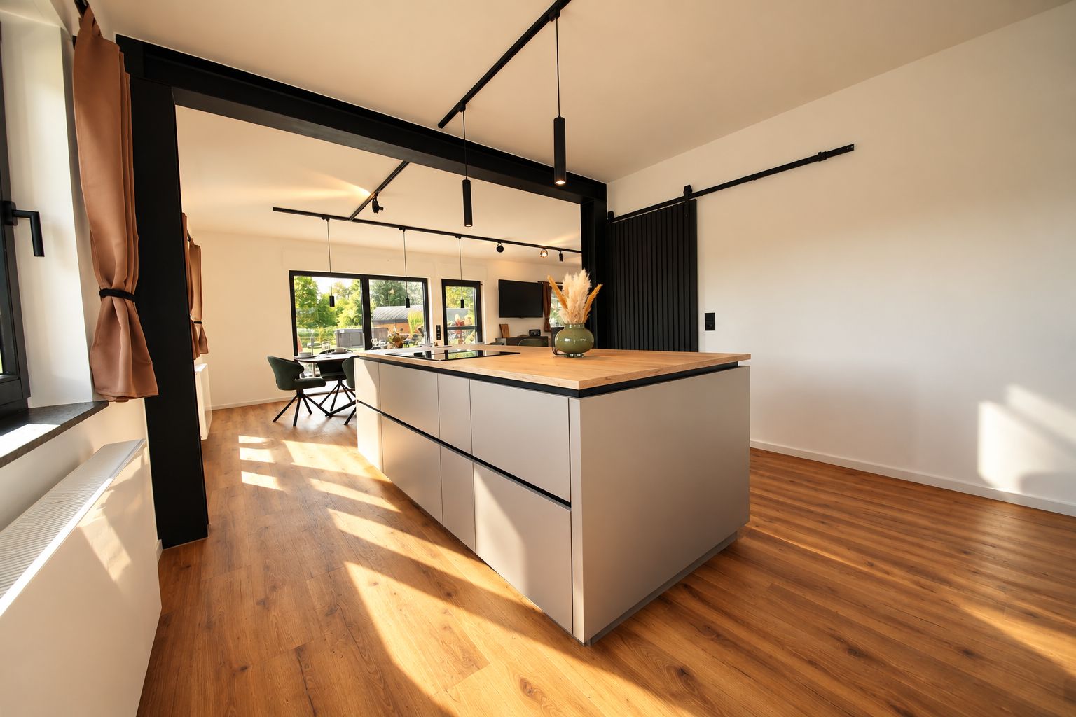 Une cuisine moderne dotée d’un îlot central, de revêtements de sol en bois et d’un coin repas avec une chaise et une table.