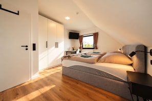 A bedroom with a bed, a desk, a TV, and a wardrobe.