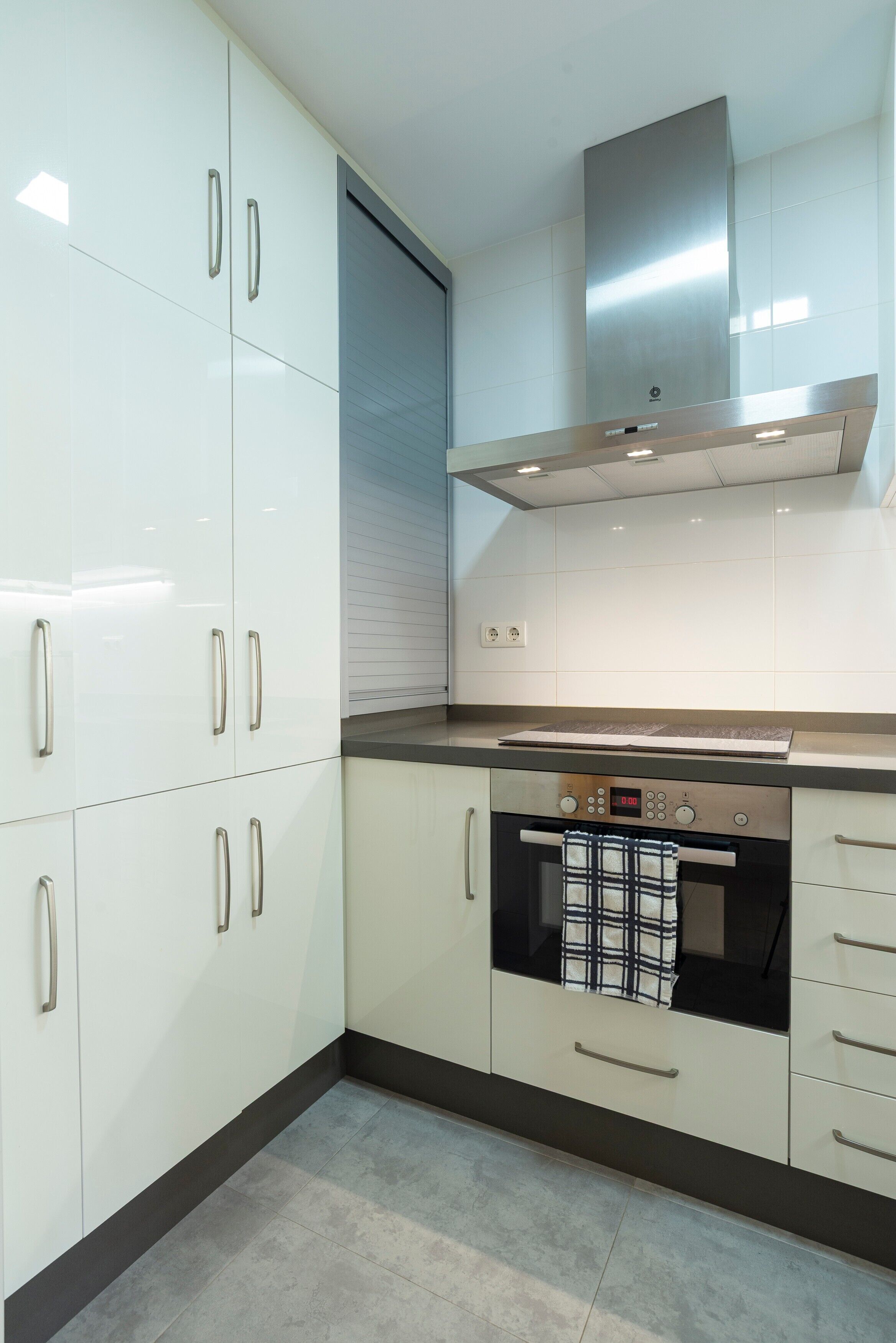 Una cocina moderna con gabinetes blancos, electrodomésticos de acero inoxidable y horno empotrado.