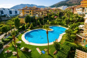 Un resort con una gran piscina, palmeras y vistas de los edificios circundantes.