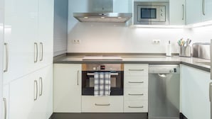 A modern kitchen with white cabinetry, stainless steel appliances, and a built-in oven. - Holiday Home 'Cozy 3BR Apartment Higuerón' with Mountain View, Wi-Fi and Air Conditioning (Benalmádena)