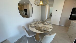 A dining area with a round table, chairs, and a mirror on the wall. - Luxury 3-bedroom apartment with panoramic views. (Calpe)