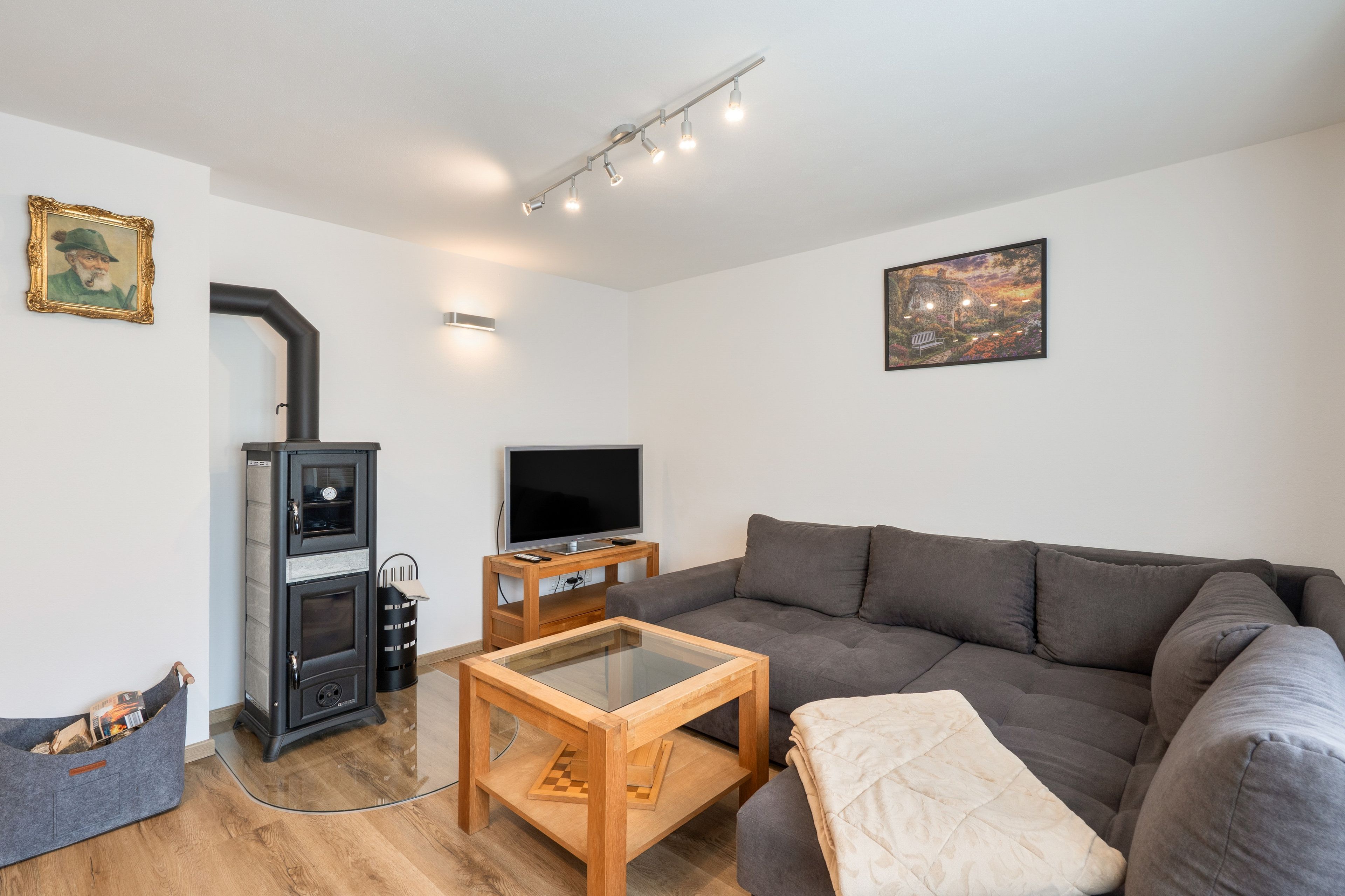 Ein Wohnzimmer mit einer Couch, einem Fernseher, einem Kamin und einem Bild an der Wand.