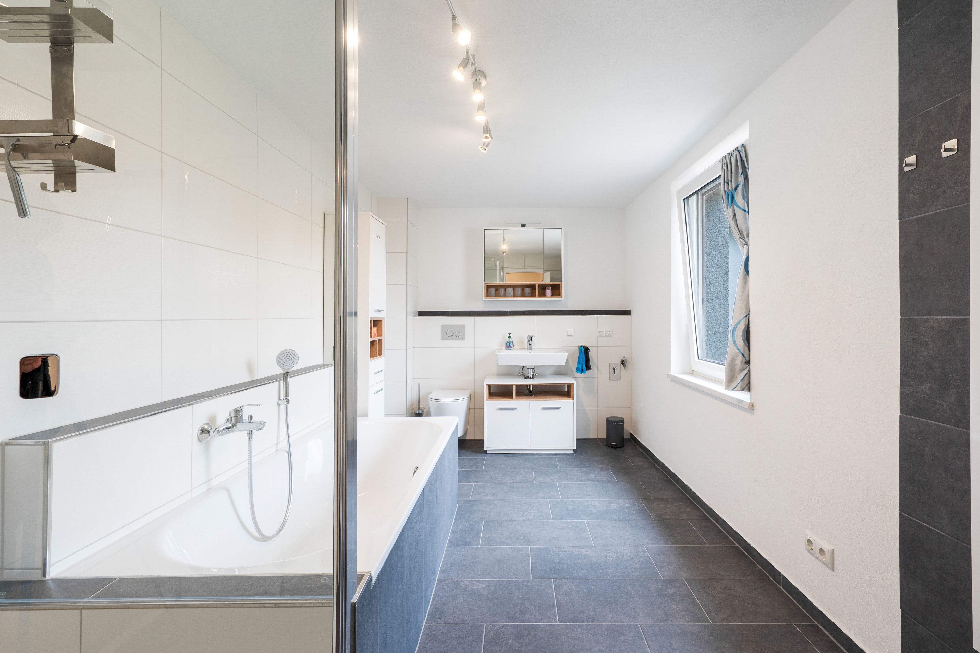 Une salle de bain moderne avec une douche à parois de verre, un lavabo blanc et un grand miroir.