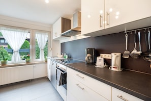 A modern kitchen with a black countertop, white cabinets, and a window with curtains.