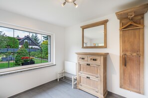 A room with a large window, a radiator, and wooden furniture including a cabinet and a wardrobe. - Holiday Home “Haus Berta” – Peaceful Location Surrounded by Nature (Spremberg)